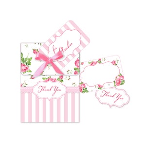 Op de afbeelding: Roze en witte gestreepte cadeauboxen met een bloemenmotief en een roze lint. De dozen hebben een "Bedankt"-label en een apart label met de tekst "voor Amber".