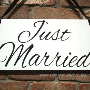 May include: White wooden sign with black text that reads 
