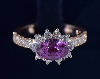 May include: A rose gold ring featuring a large oval-cut pink gemstone, surrounded by a halo of smaller white gemstones. The band is encrusted with additional white gemstones, creating a sparkling effect. The ring is set against a dark blue background.