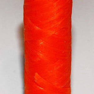 May include: A spool of bright orange thread.