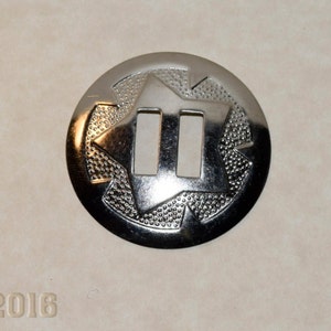 May include: Three shiny, silver-coloured metal conchos. Each concho is round with a star-like design and two rectangular cutouts. The conchos have a textured border and are displayed on a neutral background.