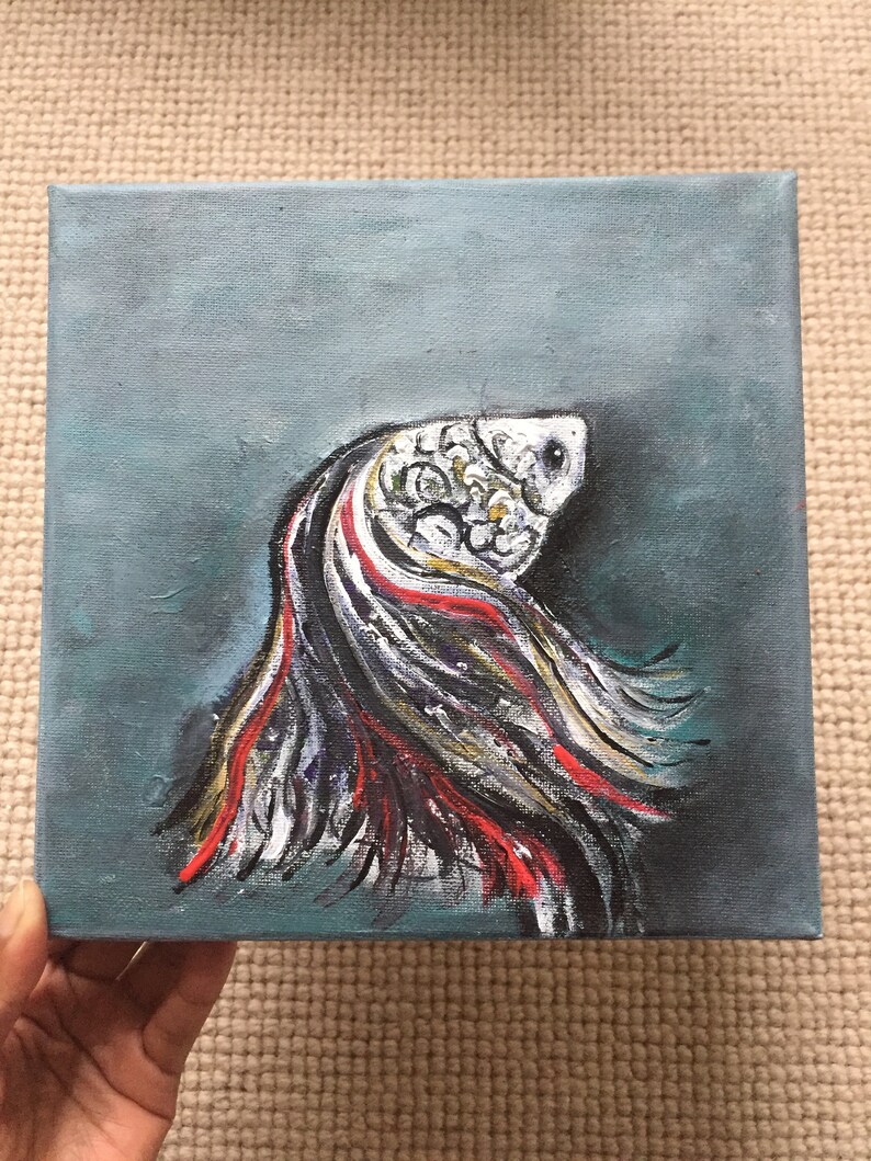 May include: A painting of a white fish with red and black fins against a teal background.