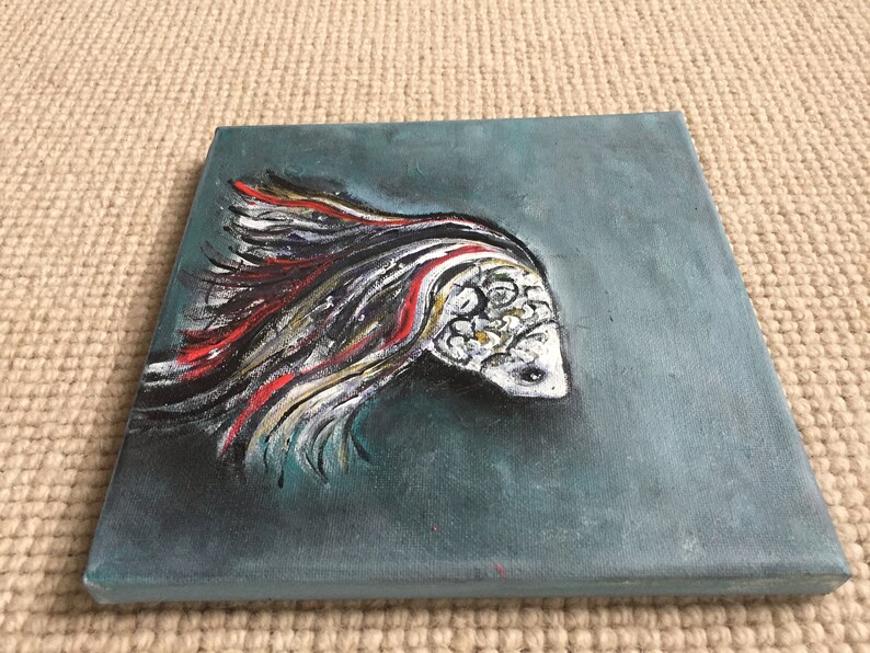 May include: A painting of a white fish with red and black stripes on a teal background.