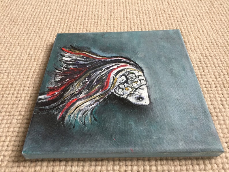 May include: A painting of a white fish with red and black stripes on a teal background.