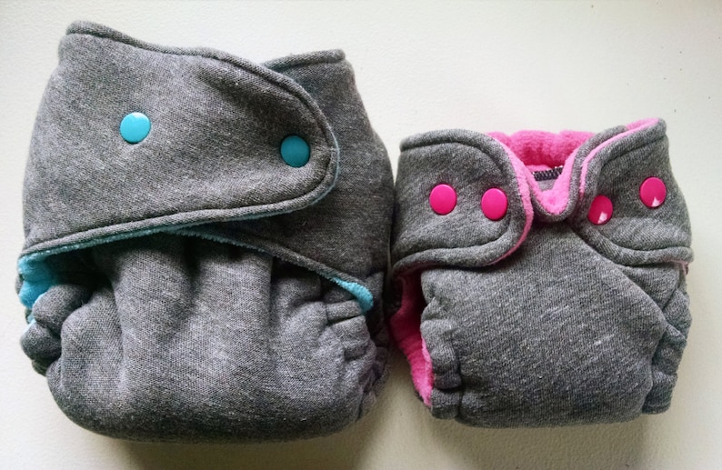 Puede incluir: Dos pa&ntilde;ales de tela grises con broches. Un pa&ntilde;al tiene broches azules y el otro tiene broches rosas.
