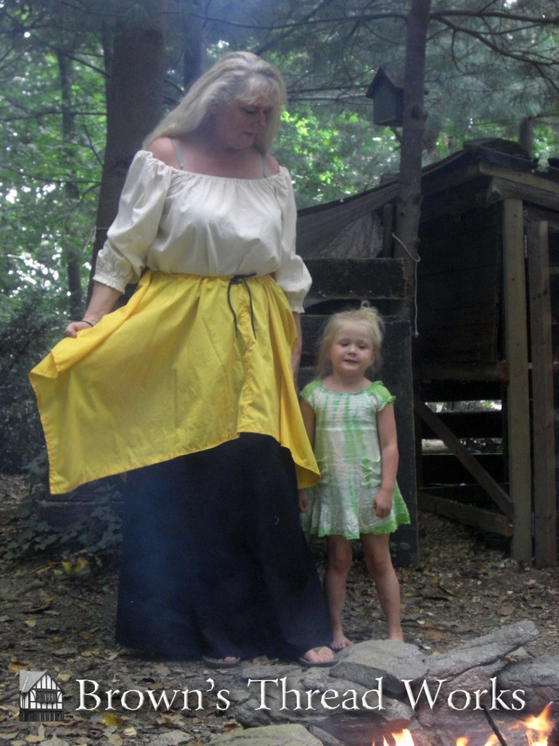 May include: A woman in a cream off-the-shoulder blouse, a yellow skirt, and a long black skirt. A young girl in a green and white dress stands nearby. The image is set outdoors with the text "Brown's Thread Works" at the bottom.