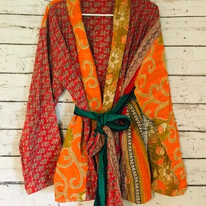 May include: A colorful patchwork kimono robe with a green sash. The robe is made of different fabrics with floral and paisley patterns in shades of red, orange, and brown.