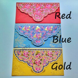 May include: Three red, blue, and gold envelopes with floral designs. The envelopes have a scalloped edge and are decorated with intricate patterns. The text "Red", "Blue", and "Gold" is written below each envelope.