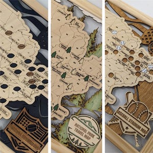 May include: A three-panel wooden wall art set featuring laser-cut maps of the United States. The panels display football stadium locations, national park sites, and baseball stadium locations with engraved text and icons in a light wood finish.