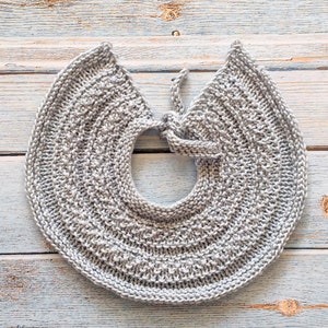 May include: A gray knitted collar with a tie closure. The collar is made of a soft, textured yarn and has a simple, elegant design.