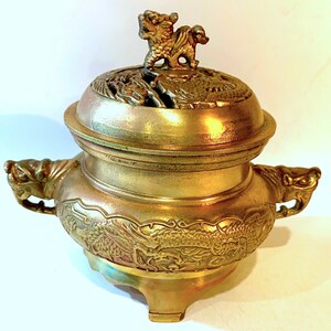 May include: A gold metal incense burner with a dragon design and a lion finial on the lid.