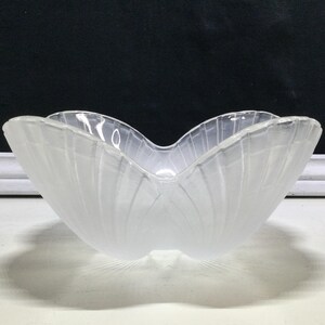 May include: A clear glass bowl with a unique, petal-like shape. The bowl has a frosted, textured surface with vertical lines, creating a delicate and elegant appearance. The bowl's design is reminiscent of a flower.