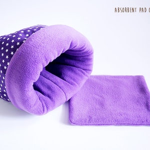 May include: Purple and white star patterned pet bed with a purple fleece lining.  The bed is shaped like a burrow and has a separate purple fleece pad.  Absorbent pad optional.