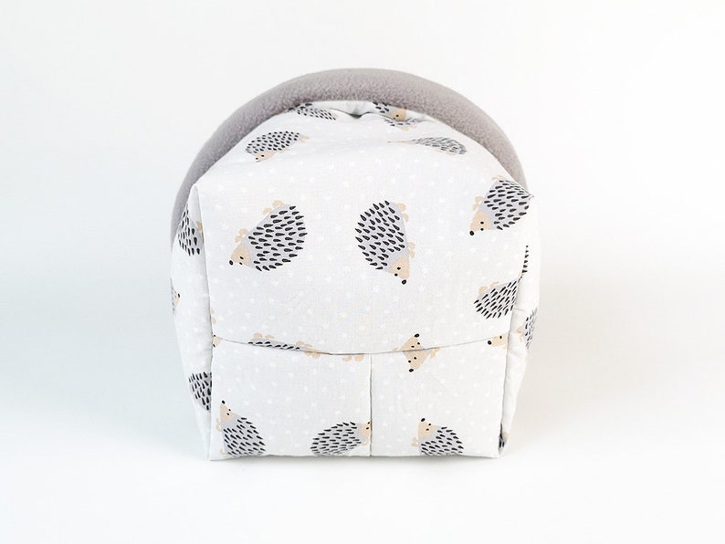 May include: A gray and white hedgehog-patterned fabric pet bed with a gray fleece lining. The bed is shaped like a house with a rounded top.