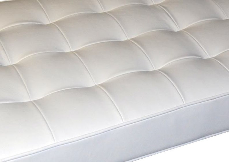 May include: White tufted upholstery with a white piping detail. The upholstery is made of a soft, smooth material.