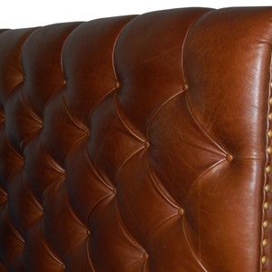 May include: A brown leather headboard with a tufted design and gold-colored nailhead trim.