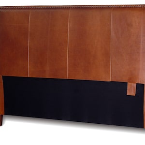May include: A brown leather headboard with a tufted design and a black fabric backing. The headboard has a simple, modern style.