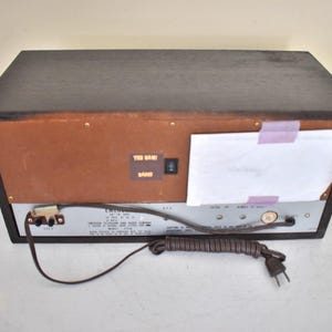 May include: A vintage brown wooden stereo receiver with a silver faceplate and a power cord. The stereo has a label that says "FM/AM Stereo Receiver" and "The Band Band".