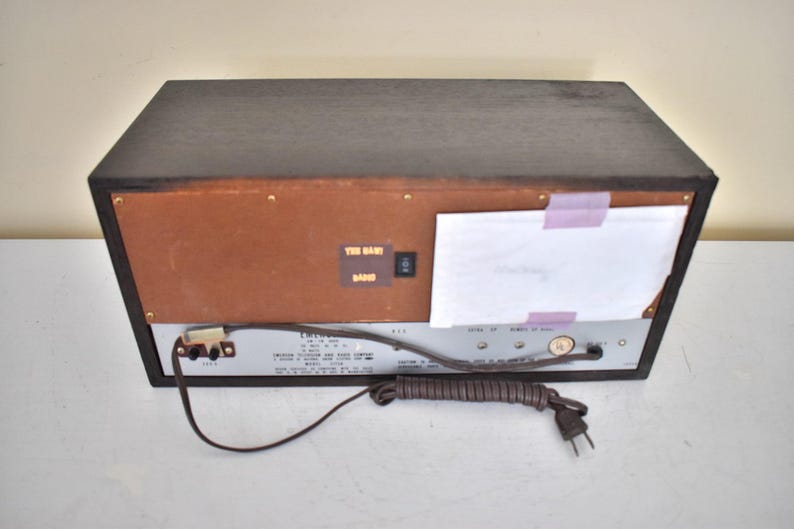 May include: A vintage brown wooden stereo receiver with a silver faceplate and a power cord. The stereo has a label that says "FM/AM Stereo Receiver" and "The Band Band".