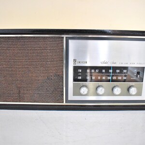 May include: A black vintage Emerson Solid State AM FM High Fidelity radio with a silver face and a brown speaker grille.