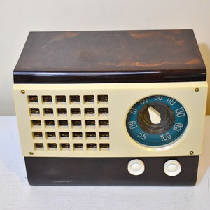 May include: A vintage, brown and cream colored radio with a blue dial and a knob for tuning. The radio has two white knobs on the front.