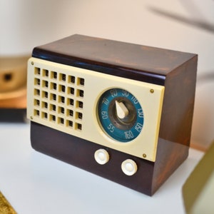 May include: A vintage brown and cream radio with a round dial and a grid of buttons. The dial has numbers from 55 to 160.