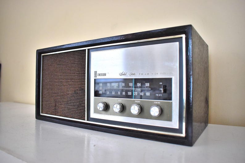 May include: A vintage black and silver Emerson "Solid State" AM/FM/High Fidelity radio with a brown speaker grille and a dial with numbers from 54 to 160.