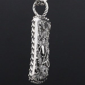 May include: A silver pendant necklace with a detailed, textured rectangular charm. The charm is covered in intricate designs and patterns, including the number "240".