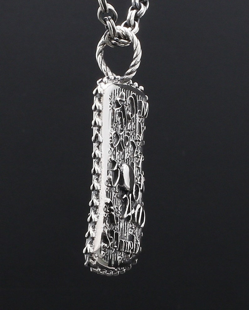 May include: A silver pendant necklace with a detailed, textured rectangular charm. The charm is covered in intricate designs and patterns, including the number "240".