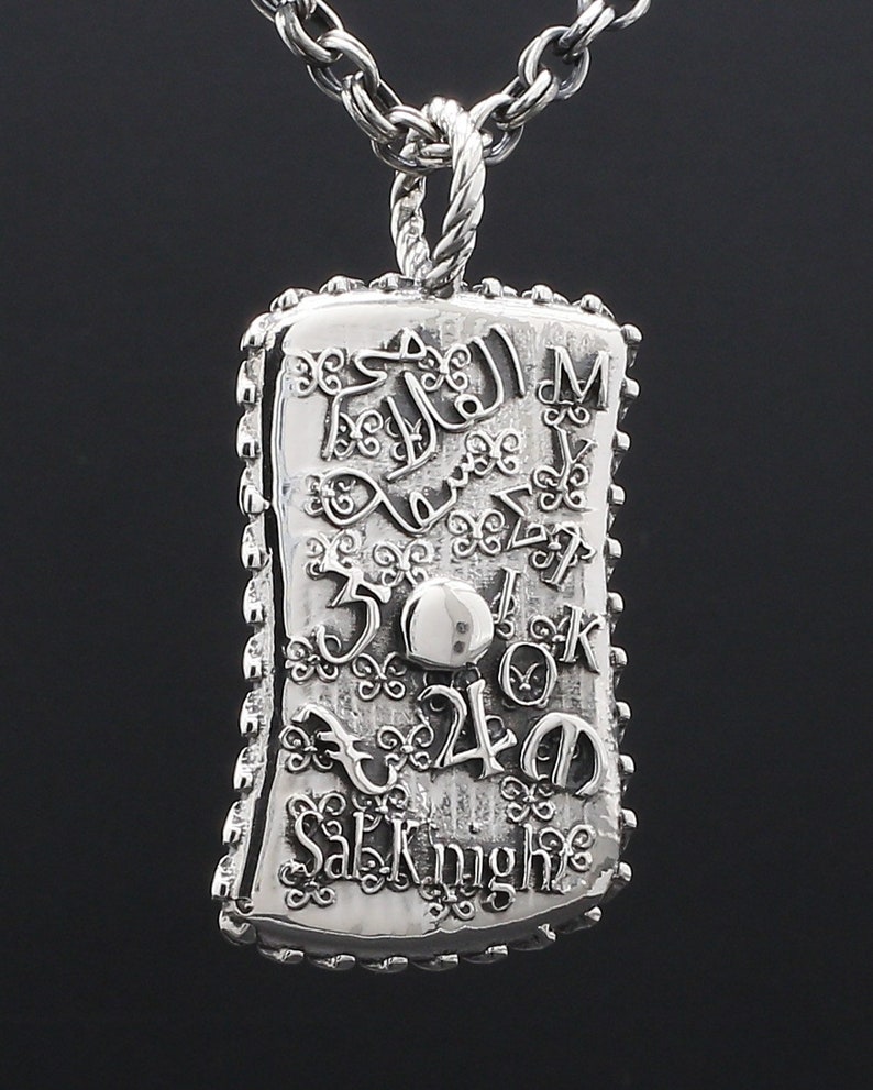 May include: Silver pendant necklace with a detailed design featuring a variety of numbers, letters, and symbols. The pendant is rectangular with a textured edge and the words "Salvatore" and "Knight" are visible.