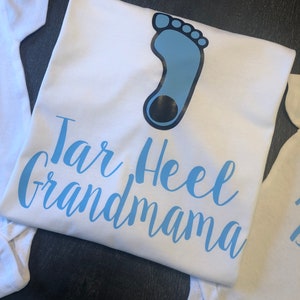 May include: White t-shirt with a blue footprint and the text "Tar Heel Grandmama" in blue lettering.