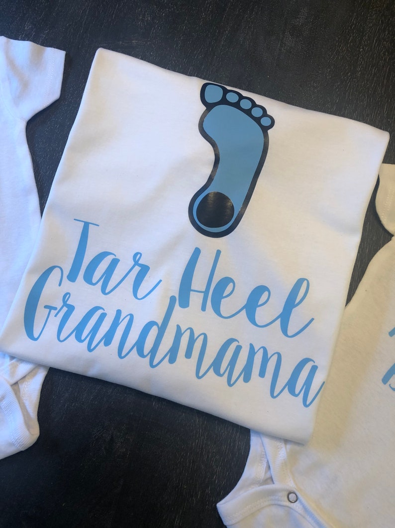 May include: White t-shirt with a blue footprint and the text "Tar Heel Grandmama" in blue lettering.