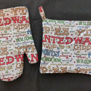 May include: A set of two white cotton pot holders with a cowboy theme. The pot holders feature red, blue, green, and yellow text and stars. The text includes phrases like "Yee-Ha Giddy", "Ya'll Come", and "Rooin Tootin Cowboy".