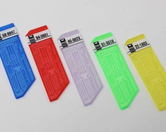 May include: Five rectangular plastic tags in blue, red, lavender, green, and yellow. Each tag features a white label at the top with a black icon and numerical codes: 58-8847, 34-0901, 40-0023, 01-5510, and 22-1903. The surface has a molded circuit pattern.