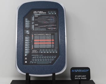 May include: A rectangular Starfleet data PADD with a dark blue textured frame and a silver border. The screen displays USS ATHENA NCC-392023, system schematics, diagnostic results, and a keyboard. It sits on a black stand with a small sign.