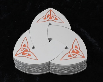 May include: A white, three-part Celtic knot design with orange knotwork details. The edges feature a gray, braided border. The design is set against a dark background, highlighting the intricate details of the artwork.