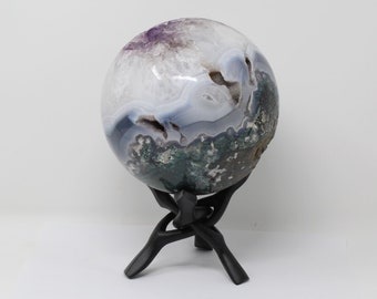 May include: A large, geode sphere with a white, blue, and green agate pattern. The sphere is on a black wooden stand.