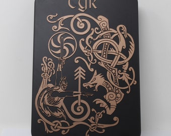 May include: A black wooden plaque with a gold-colored design of a Norse god holding a sword and a wolf. The plaque has the word "TYR" at the top.