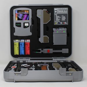 May include: A silver-colored engineering tool kit case with a black foam interior containing various technical devices, including a screen display, three colored cartridges, and a printed label reading 0963 Engineering Tool Kit.