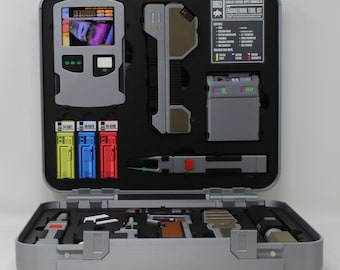 May include: A silver-colored engineering tool kit case with a black foam interior containing various technical devices, including a screen display, three colored cartridges, and a printed label reading 0963 Engineering Tool Kit.