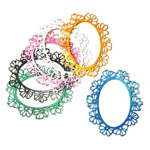 May include: A collection of oval-shaped, decorative frames in various colors, including blue, gold, pink, green, black, and white. Each frame features a floral design around the edges, creating a delicate and ornate appearance. These frames are ideal for crafting or scrapbooking projects.