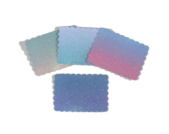 May include: Four rectangular glittery cards with scalloped edges. The cards display a gradient of colors, including blue, pink, and teal. The cards are arranged on a white background, creating a visually appealing display.