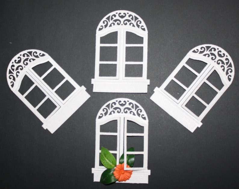 K&ouml;nnte beinhalten: Vier wei&szlig;e dekorative Fensterschnitte mit einem gew&ouml;lbten Oberteil und filigranen Schn&ouml;rkeln. Ein Fenster hat eine kleine orangefarbene Blume und gr&uuml;ne Bl&auml;tter auf der Fensterbank.