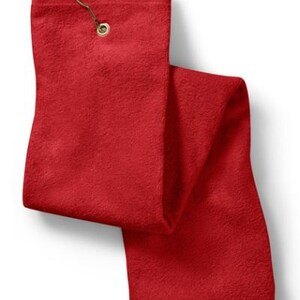Puede incluir: Una toalla de golf rectangular de color rojo s&oacute;lido con una superficie de tela texturizada. La toalla incluye un ojal de metal color lat&oacute;n en la parte superior central, equipado con un gancho de metal a juego para colgarla.