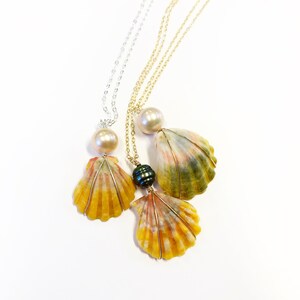 May include: Three necklaces with seashell pendants. The shells are a mix of yellow, orange, and green. The necklaces are on a white background.