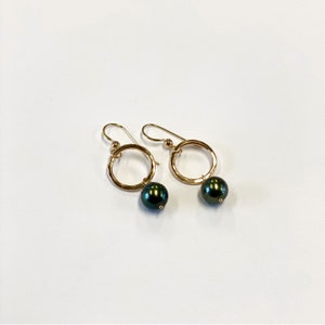 May include: Gold hoop earrings with a dark green pearl dangling from each hoop.