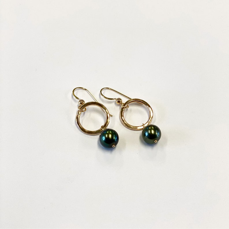 May include: Gold hoop earrings with a dark green pearl dangling from each hoop.