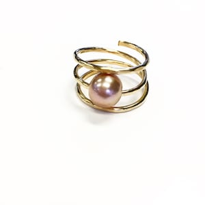 May include: A gold ring with a spiral design and a single pink pearl in the center.
