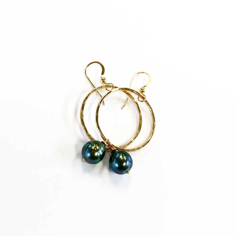 May include: Gold hoop earrings with a dark green pearl dangling from each hoop.