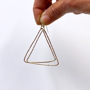 May include: Gold triangle shaped earrings with a hammered texture.